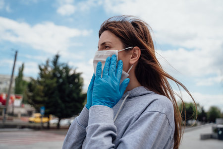 Young woman wearing protective medical mask on city street