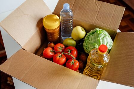 Close-up cardboard box with different fresh packed food products. Safe delivery concept. Social food donation. Safe contactless home food delivery. Selective focus.の写真素材