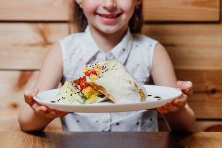 close up. little girl with vegetarian Wrap iceberg, pickled cucumbers celery carrot tofu.の写真素材