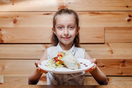 child little girl with vegetarian Wrap iceberg, pickled cucumbers, celery, carrot, tofu.の写真素材