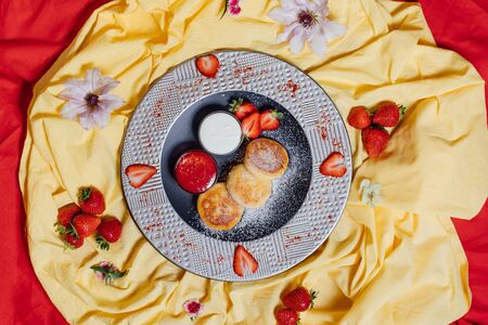 Top view of delicious dessert served on plate with bowls of strawberry jam and yoghurtの写真素材