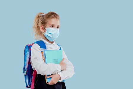 Calm blond female schoolkid with backpack on blueの写真素材