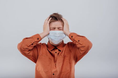 Frustrated young boy in medical face mask with eyes closed and stress due to protection against coronavirusの写真素材