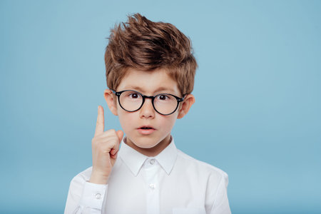 Handsome little boy in glasses is surprised on blue