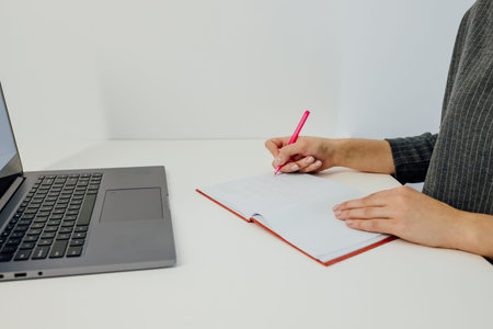 woman hand writing in notebook, with laptop, top view, e-learning concept,
