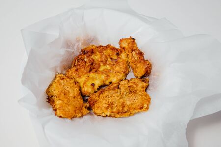High angle of appetizing roasted chicken in batter on napkin in bowl on white background in studioの写真素材