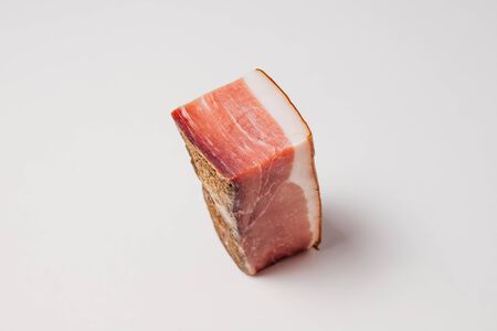High angle of piece of pork meat with thin layer lard of and smoke dried crust with spice on white table in modern kitchenの写真素材