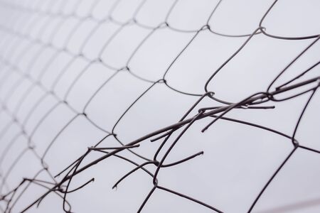 Closeup from below wet wire connections of chain link fence against gray sky on rainy dayの写真素材