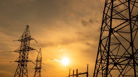 electricity pylons and high voltage power line at sunset. Five electricity pylons in a row on the background of beautiful cloudy sky.の写真素材