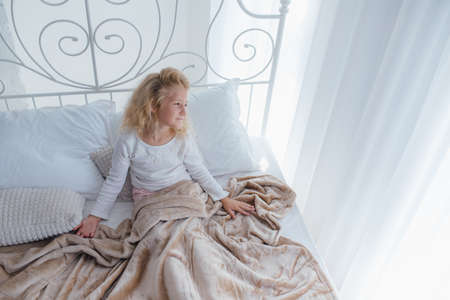 front view, little girl who is in bed early in the morning, the child wakes upの写真素材
