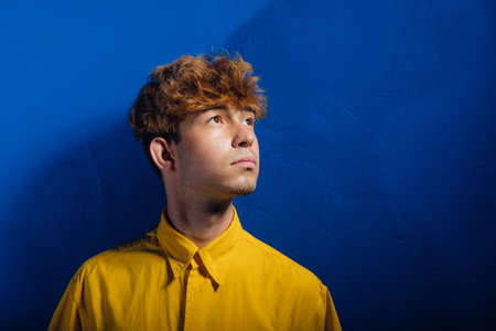 front view, teenager in yellow shirt, young guy, attractive young man, young man with fashionable hairstyle, blue background, studio shotの写真素材