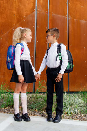 little schoolchildren look at each other. two schoolchildren, a boy and a girl, hold handsの写真素材