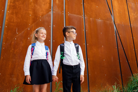 two schoolchildren boy and girl, little schoolchildren, little schoolchildren are returning from school. two schoolboys, a boy and a girl, hold handsの写真素材