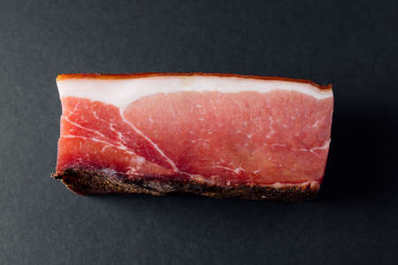 High angle of piece of pork meat with thin layer lard of and smoke dried crust with spice on gray table in modern kitchenの写真素材
