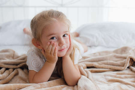 front view, the little girl is in her bed, in the morning, she looks suspiciously at the cameraの写真素材