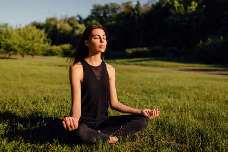 Young woman practicing yoga outdoors. Harmony and meditation concept. Healthy lifestyleの写真素材