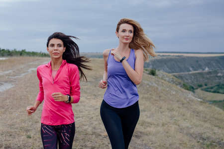 two Young women are exercising with outdoor running When the sun sets in  in summer, Concept healthy running and outdoor exercise,Tracking dolly shotの写真素材