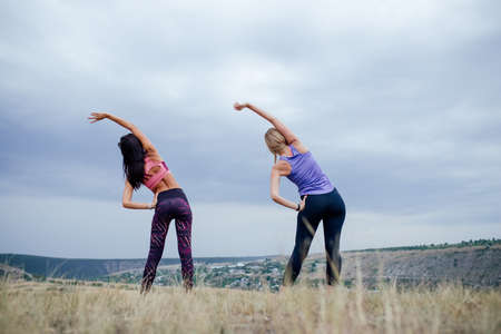 rear view of a Sport two women. Young people women sports exercises together at fitness training outdoor. two girl at sport training togetherの写真素材