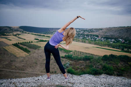 Young female workout before fitness training session, Healthy young woman warming up outdoors. She is stretching her armsの写真素材