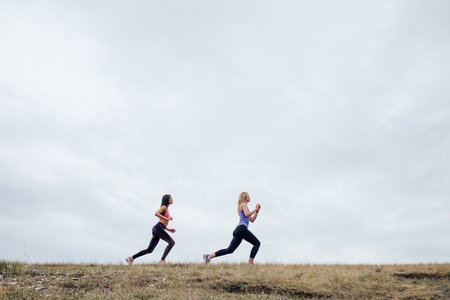 side view, Sport two women. Young people women sports exercises together at fitness training outdoor. two girl at sport training togetherの写真素材