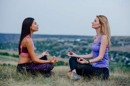 Woman doing outdoor yoga. Outdoor Yoga. Two woman are engaged in yoga in outdoor settingの写真素材