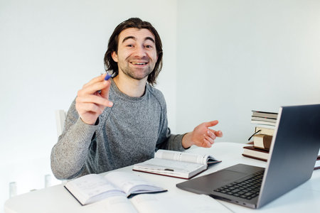 Online education. Young attractive man is engaged in an individual lesson with a student on video...
