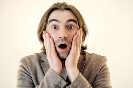 Amazed caucasian man shocked, saying WOW. Handsome guy with stylish hairdo surprised to camera over yellow background.の写真素材