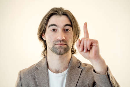 Portrait of a young businessman having idea and pointing finger up. guy raise index finger up wear casual style jacket in studioの写真素材