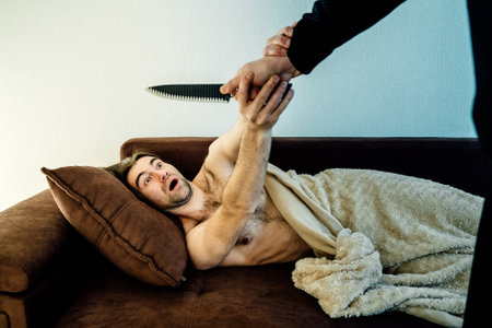 male Trying To Kill Man who sleeps With Knife. scared man defends himself from killerの写真素材
