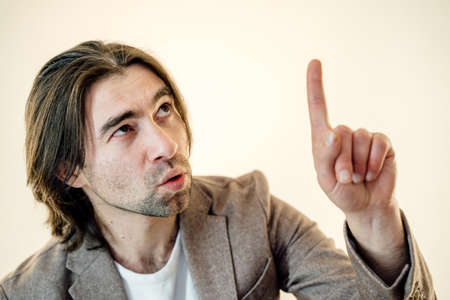 millennial guy hand raise index finger up have amazing creative blog post idea wear casual style jacket in studioの写真素材