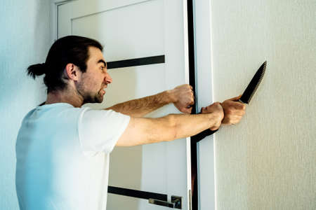 Crime Concept. human hands with knife ready to attack man who who keeps the door in the houseの写真素材