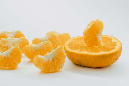 tangerine or mandarin fruit isolated on white background cutout. Five peeled pieces of orange or tangerine fruit in the air on white background with clipping pathの写真素材