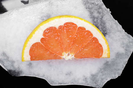 Close up fresh citrus fruit slice, pink grapefruit, over background of slice ice, elevated high angle view, directly aboveの写真素材