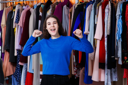happy beautiful caucasian teen enjoying everyday life moments - Looking at camera. Beautiful young woman near rack near hangers with clothing. shopping, fashion, style and people conceptの写真素材
