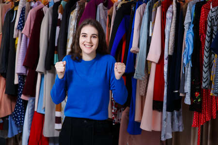 happy beautiful caucasian teen enjoying everyday life moments - Looking at camera. Beautiful young woman near rack near hangers with clothing. shopping, fashion, style and people conceptの写真素材