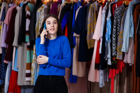 portrait of a young stylish teenager woman using a smartphone device, Beautiful girl front of modern clothes wardrobe closet in the shopping store. shopping, fashion, style and people conceptの写真素材