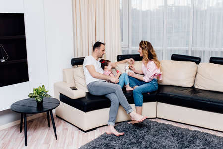 Young family on sofa in the living room, father, daughter and mother being playful at home. Weekend activity happy family lifestyle conceptの写真素材