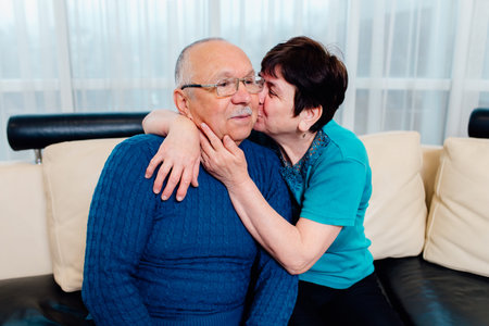 senior couple in love. Charming bewitching cheerful black-haired female tenderly kissing her aged...
