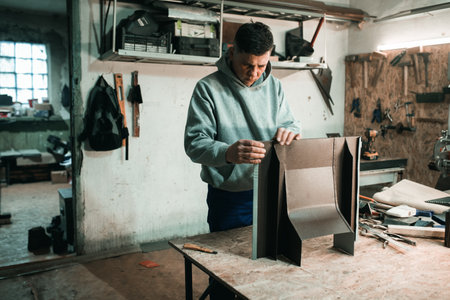 Portrait of a real tinsmith blacksmith of a man who works with metal in his workshop, makes measurements with a ruler Portrait of a profession.の写真素材