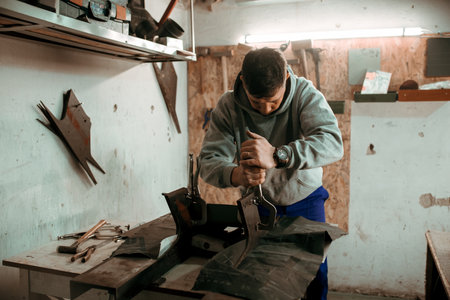 tinsmith blacksmith use hammer working in his workshop. Blacksmiths workshop. young tinsmith in his workshop.の写真素材