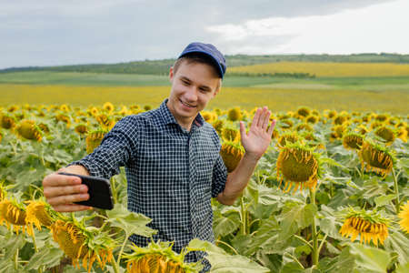 young agronomist leads a vlog in the sunflower field, modern farmer using social media for marketingの写真素材