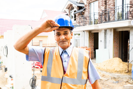 people working in construction site. Portrait of happy indian man at work in new house. Professional...