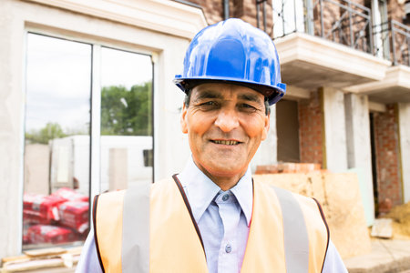 Portrait of confident indian male construction worker at construction site. Confident construction...