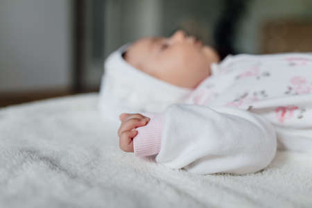 selective focus of a body part of a baby, close up of a baby hand arm on white background. baby sleepsの写真素材