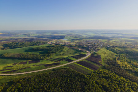 Aerial View Of Road Between agricultural Fields at sunset. Flight with a camera drone over a asphalt...