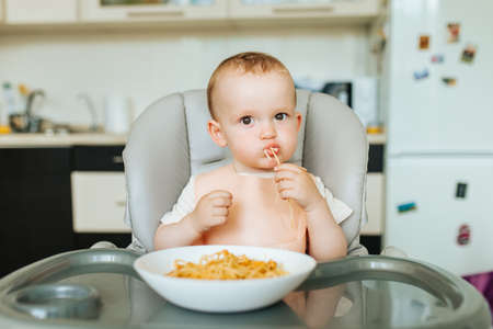 Little baby boy eating spaghetti dinner and making a mess. nice child eating healthy organic and vegan foodの写真素材