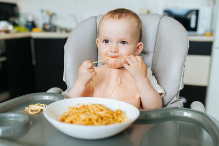 Little baby boy eating spaghetti dinner and making a mess. nice child eating healthy organic and vegan foodの写真素材