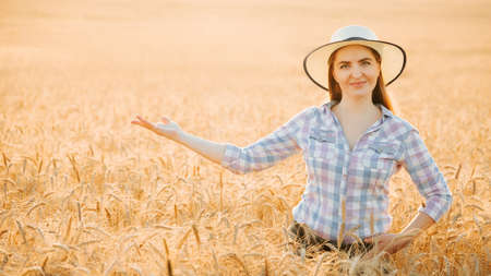 Portrait of smiling beautiful female farmer with outstretched hand. Woman at wheat field in summer day at sundown. american young woman. Latino people.の写真素材