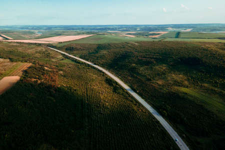 aerial view of the road that crosses the fields with different crops. the flight of the drone over the agro-industrial lands,の写真素材