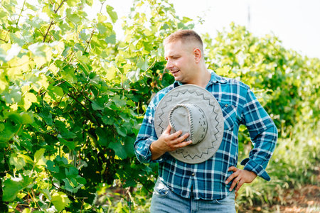 serious modern and young farmer with hat, winery and winemaker. caucasian man